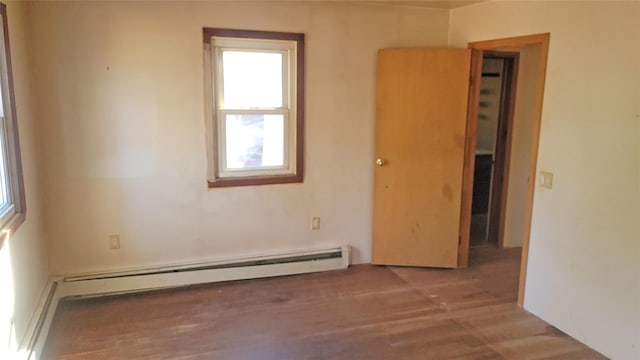 unfurnished room featuring a baseboard heating unit and wood finished floors