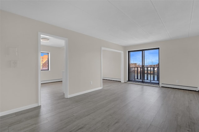 spare room with baseboards, baseboard heating, and wood finished floors