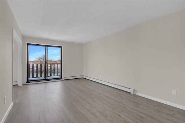 spare room with baseboards, baseboard heating, and wood finished floors