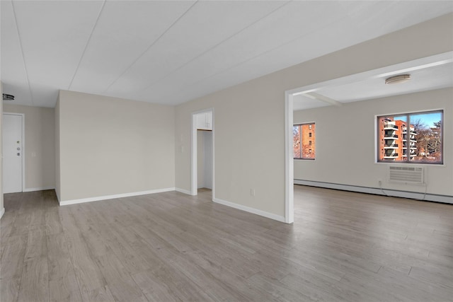 spare room with a baseboard heating unit, wood finished floors, and baseboards