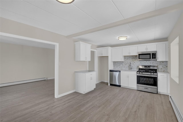 kitchen with a baseboard heating unit, appliances with stainless steel finishes, backsplash, and light wood-style flooring