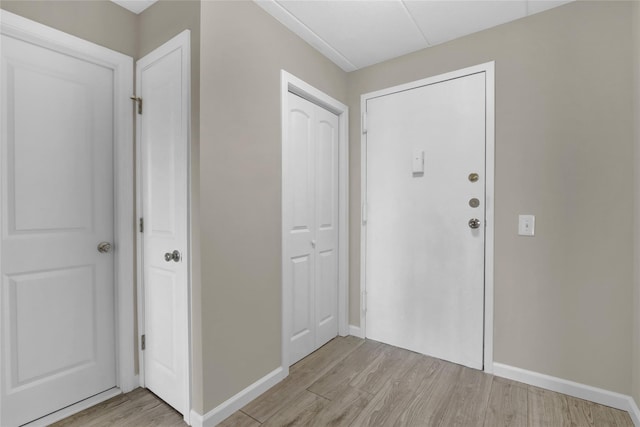 foyer entrance with light wood-style flooring and baseboards