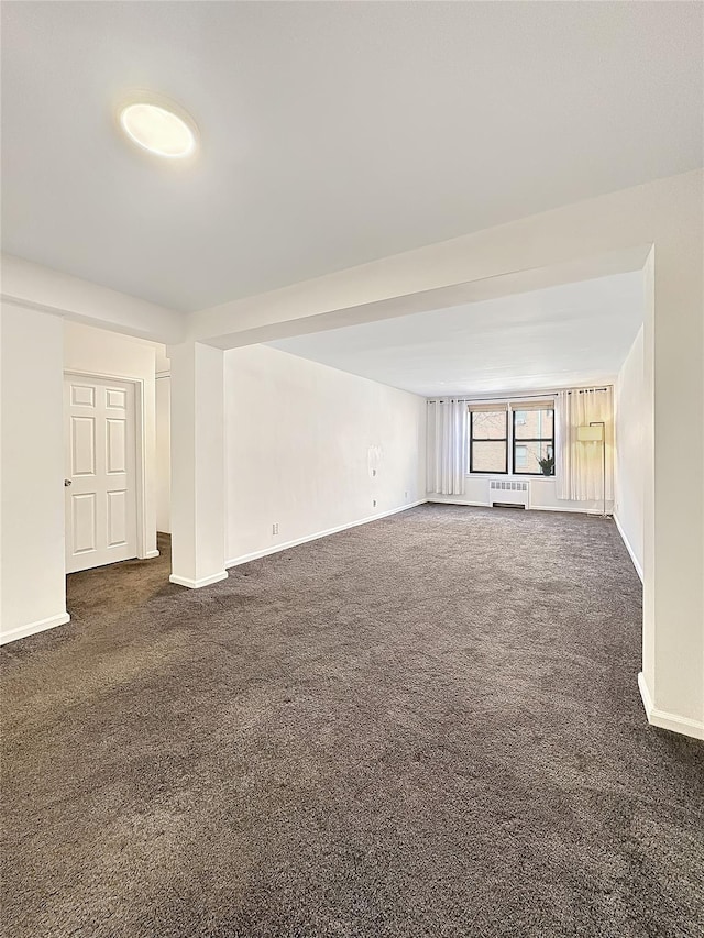 unfurnished living room with dark colored carpet and baseboards