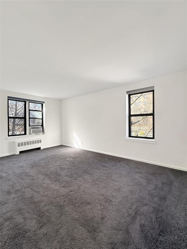 spare room featuring cooling unit, radiator, dark carpet, and baseboards