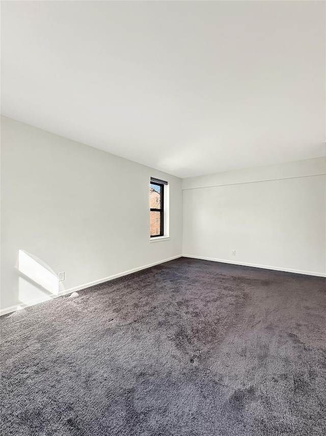 carpeted empty room featuring baseboards