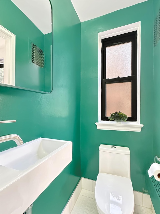 bathroom with toilet, tile patterned flooring, baseboards, and a sink