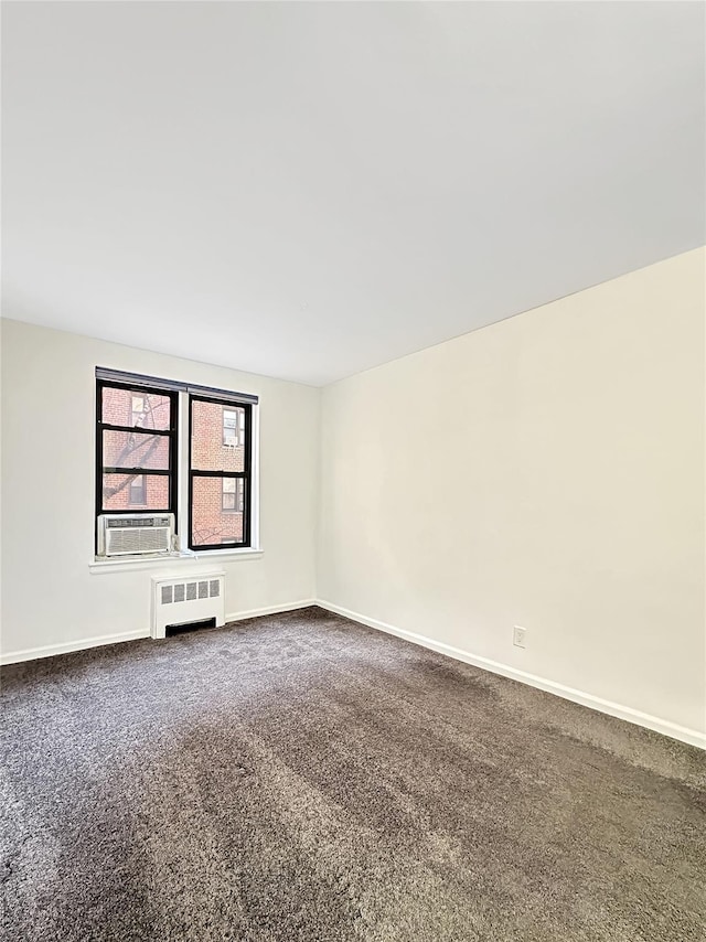 empty room with cooling unit, radiator, dark carpet, and baseboards