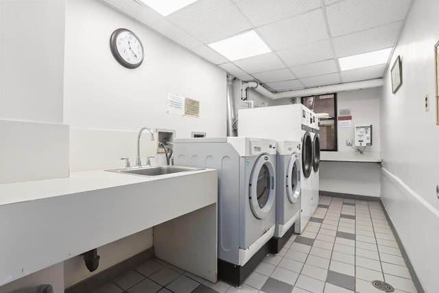 common laundry area featuring light tile patterned floors, a sink, baseboards, and separate washer and dryer