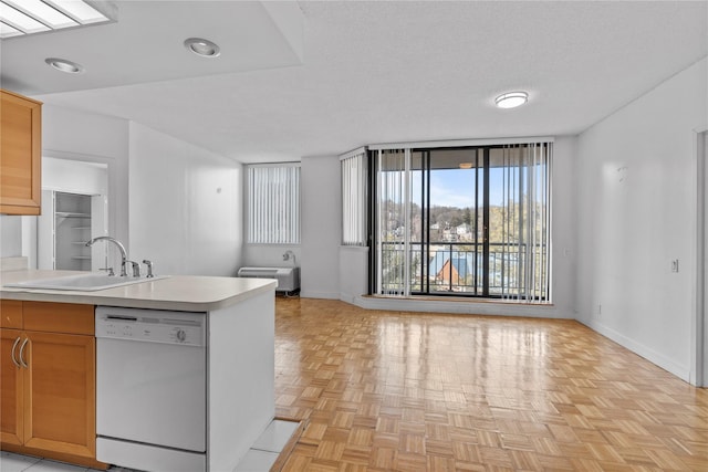 kitchen featuring white dishwasher, a sink, baseboards, open floor plan, and light countertops