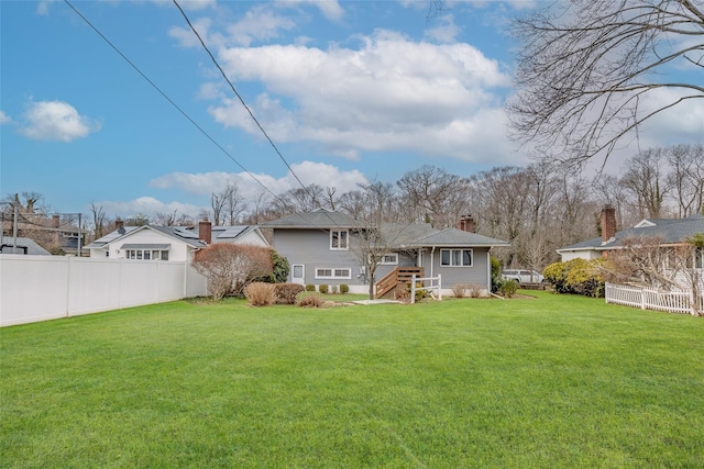 rear view of property with a yard, a chimney, and fence