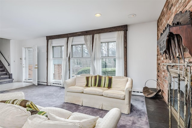 carpeted living area featuring a baseboard heating unit, a fireplace, stairway, and brick wall