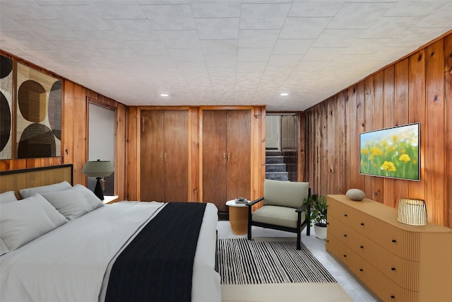 bedroom with light carpet, recessed lighting, and wooden walls