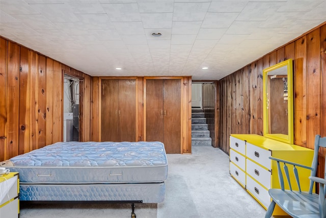 bedroom with wood walls and light colored carpet