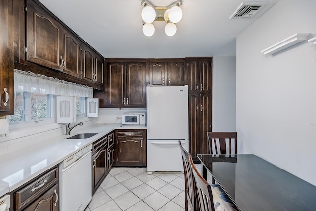 kitchen with dark brown cabinetry, white appliances, visible vents, a sink, and light tile patterned flooring