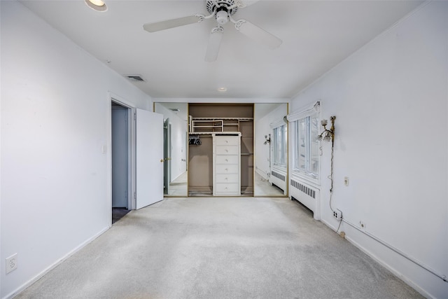 unfurnished bedroom featuring a closet, visible vents, radiator heating unit, a ceiling fan, and light carpet