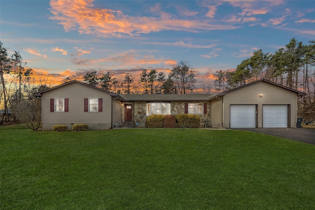 ranch-style house featuring aphalt driveway, a garage, and a front lawn