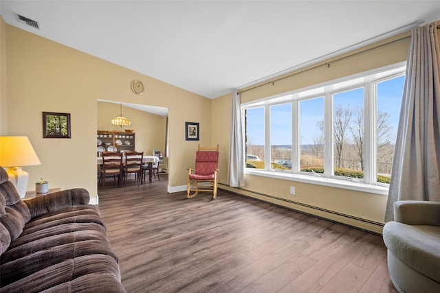 living area featuring visible vents, wood finished floors, a baseboard heating unit, and vaulted ceiling