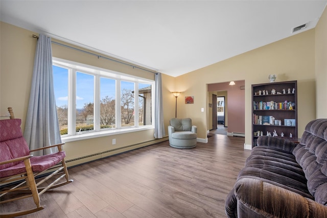 living room featuring visible vents, lofted ceiling, baseboard heating, and wood finished floors