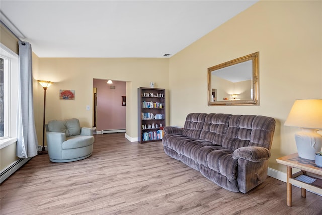 living area with a baseboard heating unit, wood finished floors, visible vents, and baseboards