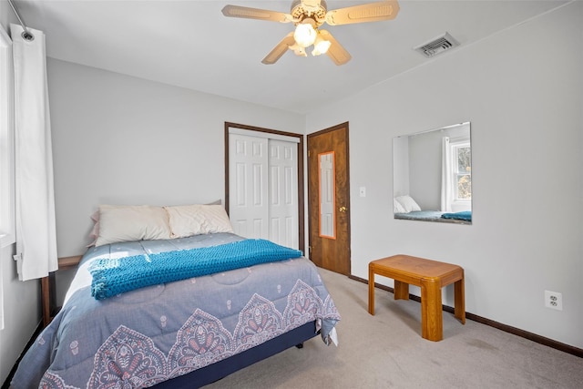 carpeted bedroom with visible vents, baseboards, a closet, and a ceiling fan