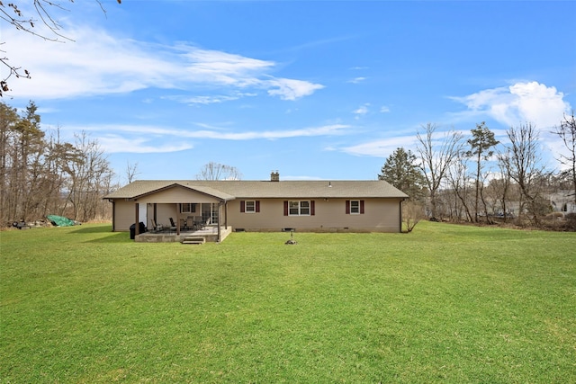 rear view of house with crawl space, a yard, a chimney, and a patio area