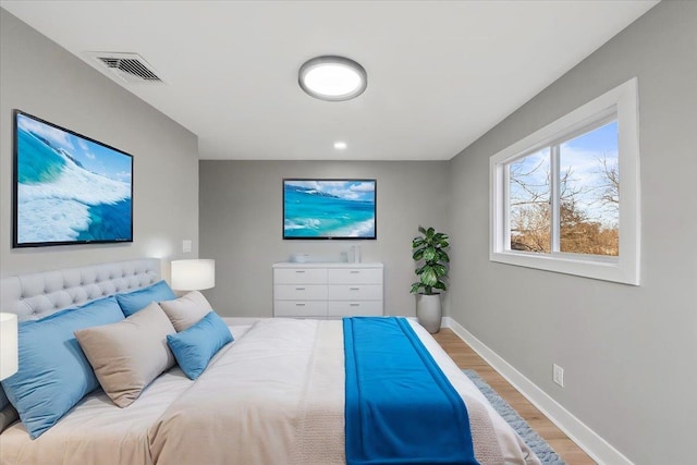 bedroom with wood finished floors, visible vents, and baseboards