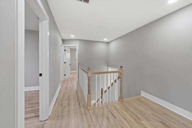 hallway with recessed lighting, baseboards, an upstairs landing, and wood finished floors