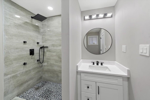 bathroom with tiled shower and vanity