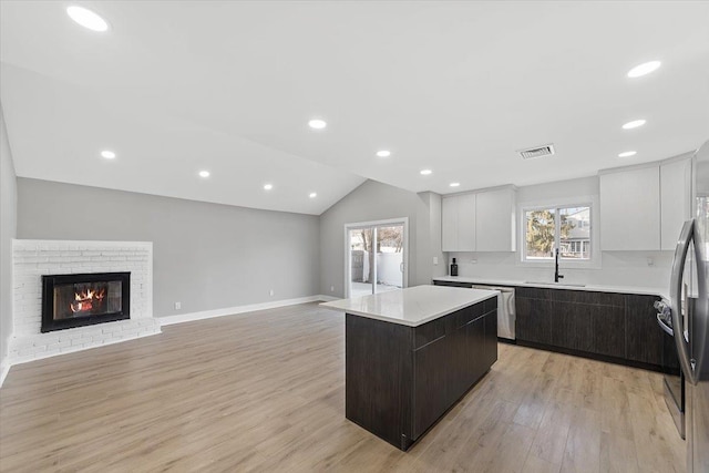 kitchen featuring stainless steel appliances, light countertops, visible vents, a kitchen island, and a sink