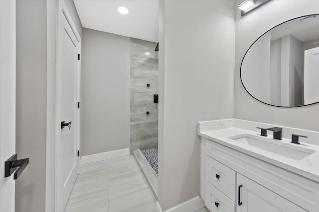 full bathroom featuring recessed lighting, tiled shower, vanity, and baseboards