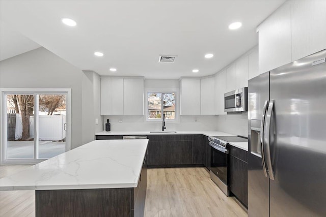 kitchen featuring light wood finished floors, visible vents, white cabinets, stainless steel appliances, and a sink