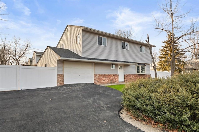 view of front facade with a garage, brick siding, fence, and driveway