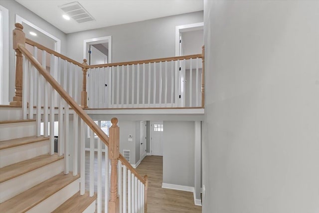 stairs featuring a towering ceiling, baseboards, visible vents, and wood finished floors