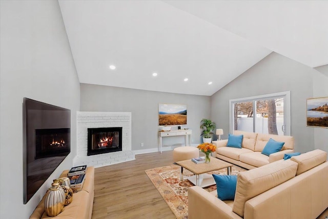 living room featuring baseboards, light wood-style flooring, a brick fireplace, high vaulted ceiling, and recessed lighting