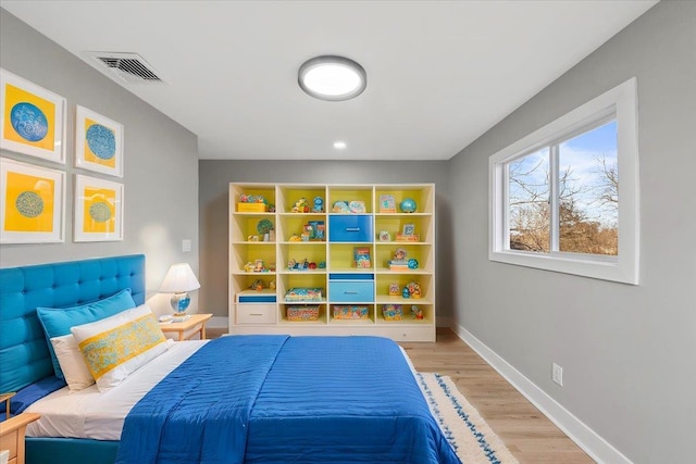 bedroom featuring light wood-style flooring, visible vents, and baseboards