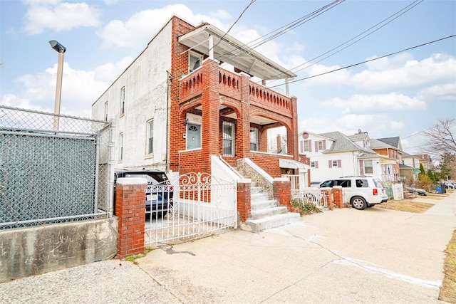 view of front of home with a balcony, brick siding, and fence