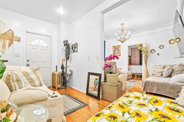 living room with crown molding, light wood-type flooring, and a chandelier