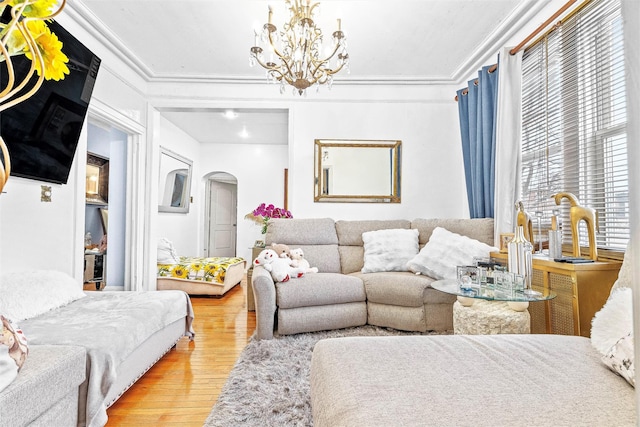 bedroom with arched walkways, a chandelier, light wood finished floors, and ornamental molding