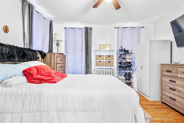 bedroom with radiator, light wood-style floors, and a ceiling fan