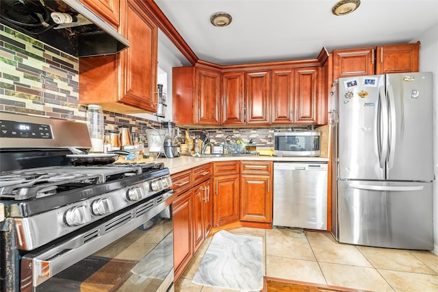 kitchen featuring under cabinet range hood, backsplash, appliances with stainless steel finishes, light countertops, and light tile patterned floors