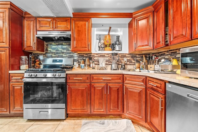 kitchen with under cabinet range hood, a sink, appliances with stainless steel finishes, light countertops, and light tile patterned floors