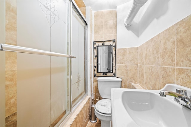 bathroom with toilet, tile walls, and a sink