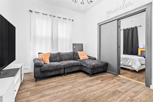 living area featuring light wood-style flooring, baseboards, and an inviting chandelier