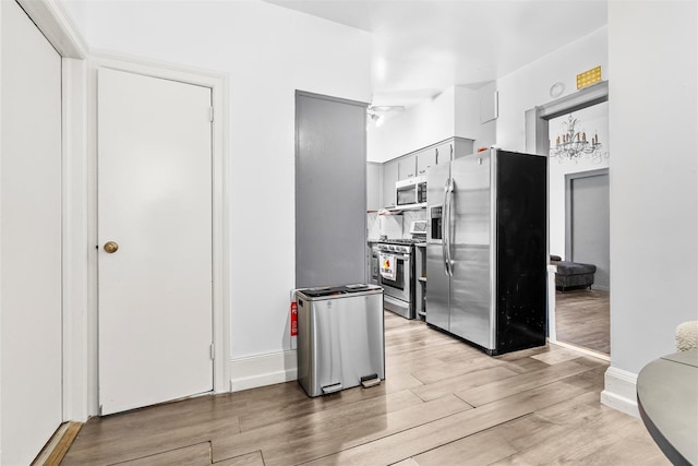 kitchen with light wood-style floors, baseboards, and appliances with stainless steel finishes