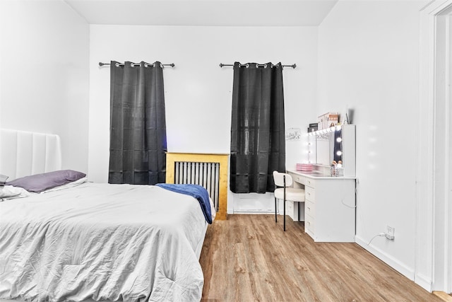 bedroom with wood finished floors and radiator heating unit