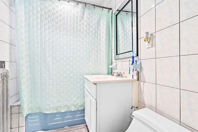 bathroom featuring vanity, tile walls, toilet, and shower / bath combo with shower curtain