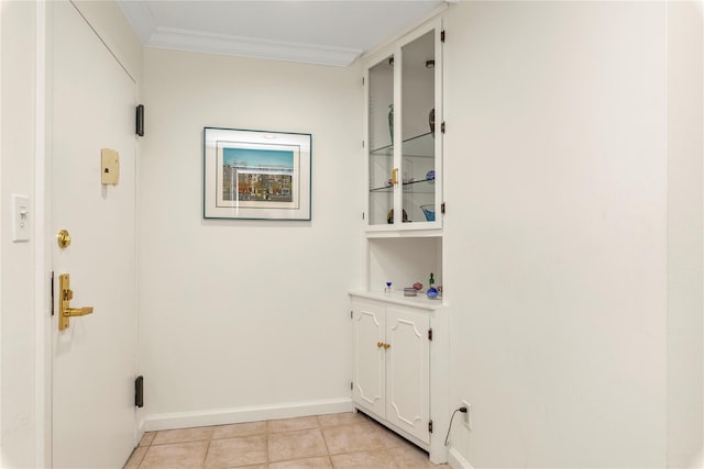 clothes washing area featuring baseboards, light tile patterned flooring, and crown molding