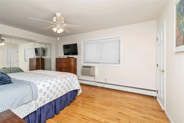 bedroom with ceiling fan, a baseboard radiator, a wall unit AC, light wood-style floors, and a closet