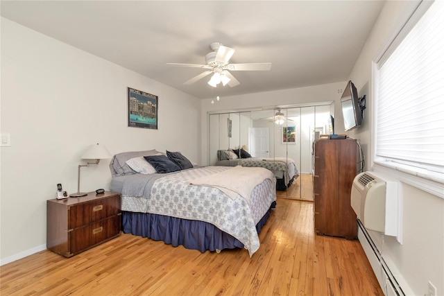 bedroom featuring ceiling fan, baseboards, baseboard heating, a closet, and light wood-type flooring