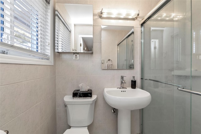 bathroom featuring toilet, a stall shower, and tile walls